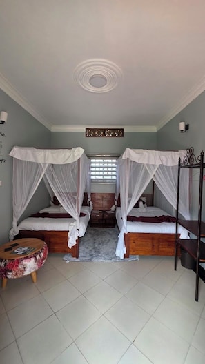 A room with two beds, each with a canopy, a small round table, and a window with blinds. - Nkokonjeru White Cove Mbarara (Mbarara)
