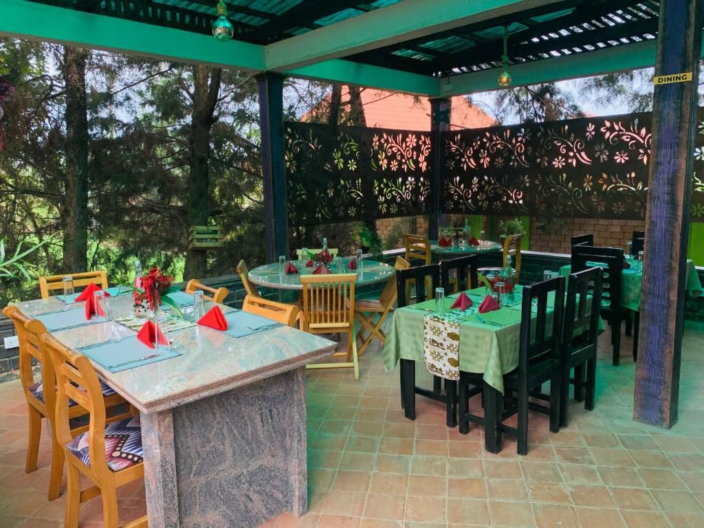 An outdoor dining area with tables and chairs, a pergola structure, and a view of trees.