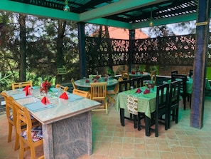 An outdoor dining area with tables and chairs, a pergola structure, and a view of trees. - Nkokonjeru White Cove Mbarara (Mbarara)