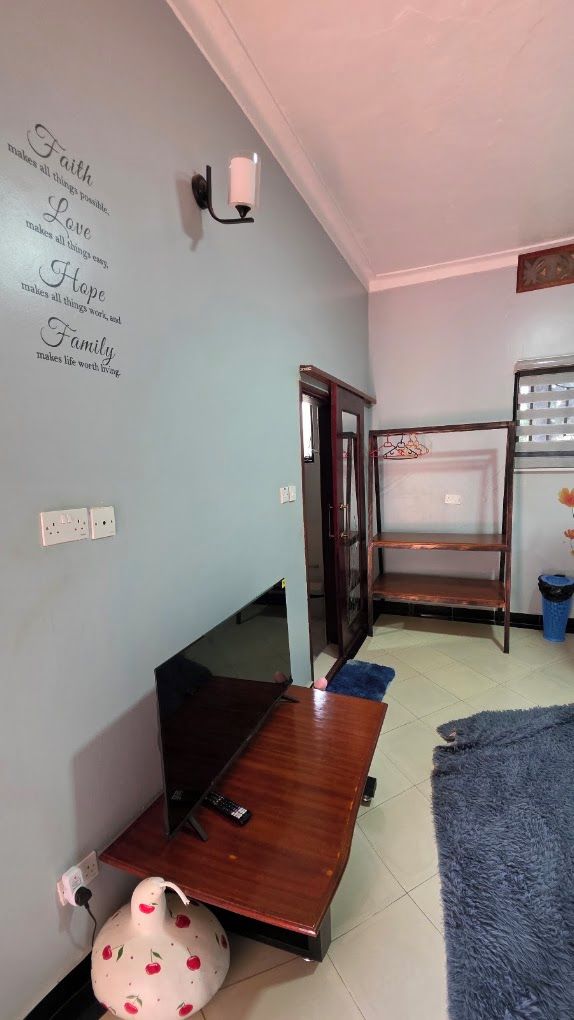 A room with a bed, a desk, a wall-mounted light, and a wall with inspirational quotes.