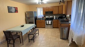 A compact kitchen with a dining table, chairs, a refrigerator, an oven, and a microwave.