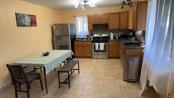 A compact kitchen with a dining table, chairs, a refrigerator, an oven, and a microwave.