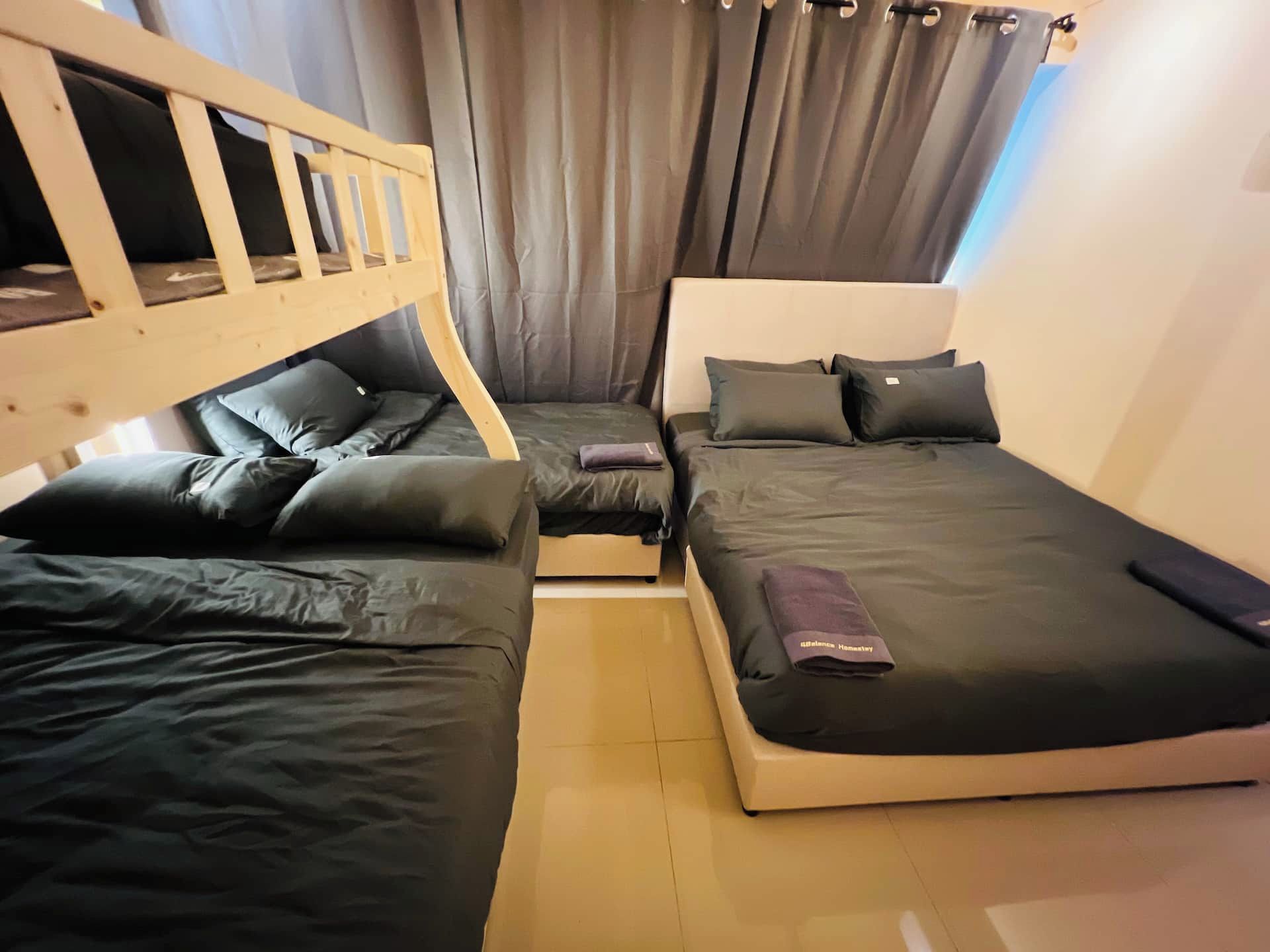 A room with two beds, a wooden headboard, and a curtain.