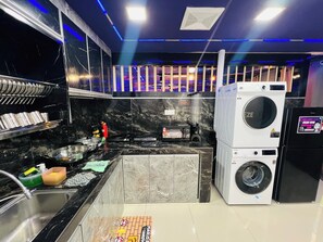 Cozinha compacta com máquina de lavar, micro-ondas e pia.