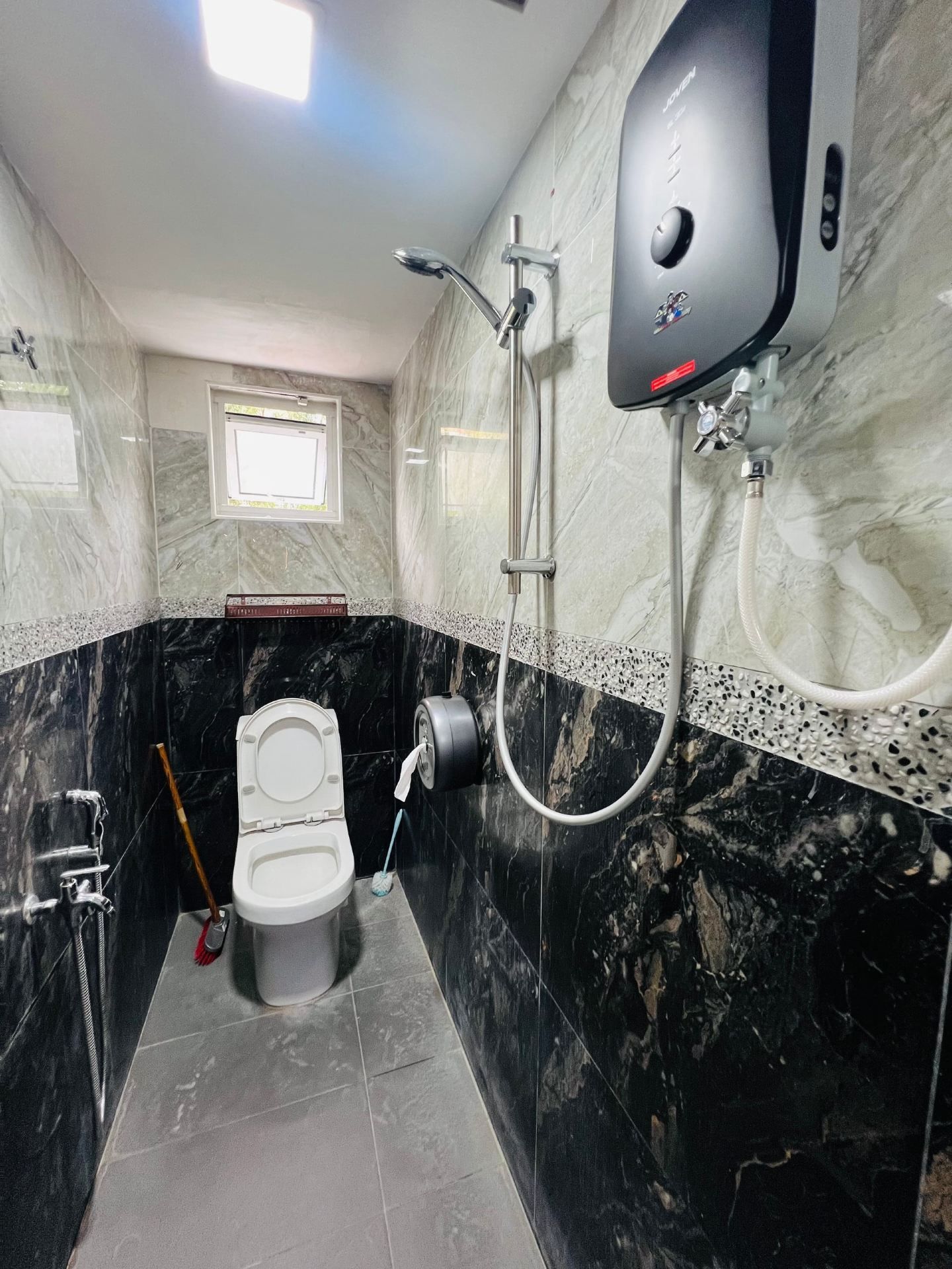 A bathroom with a toilet, a shower, and a hand dryer mounted on the wall.