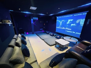 Une salle de cinéma privée équipée d’un grand écran, de sièges confortables et d’un panneau de commande.