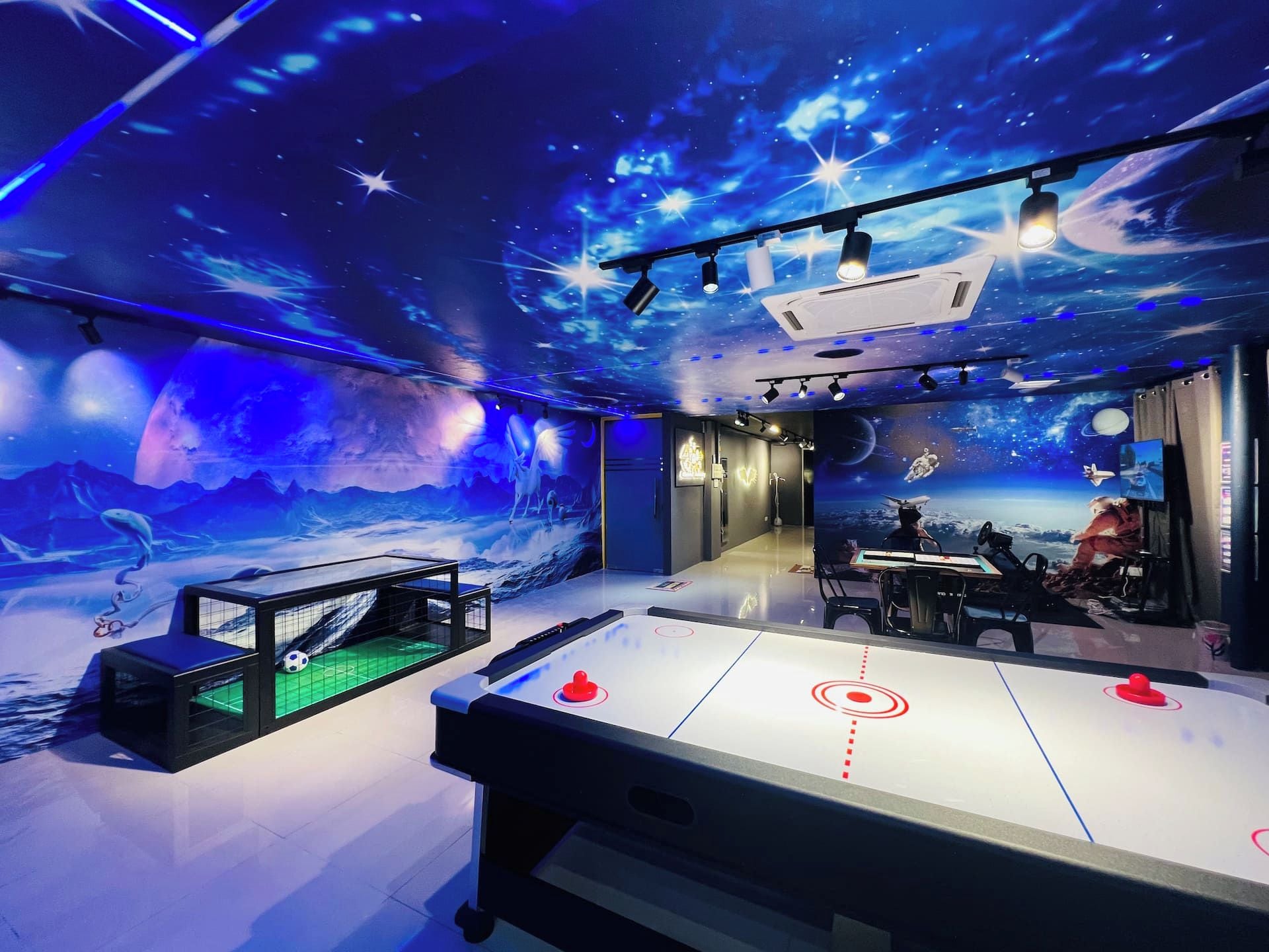 A room with a space-themed mural, a foosball table, and a table tennis table.