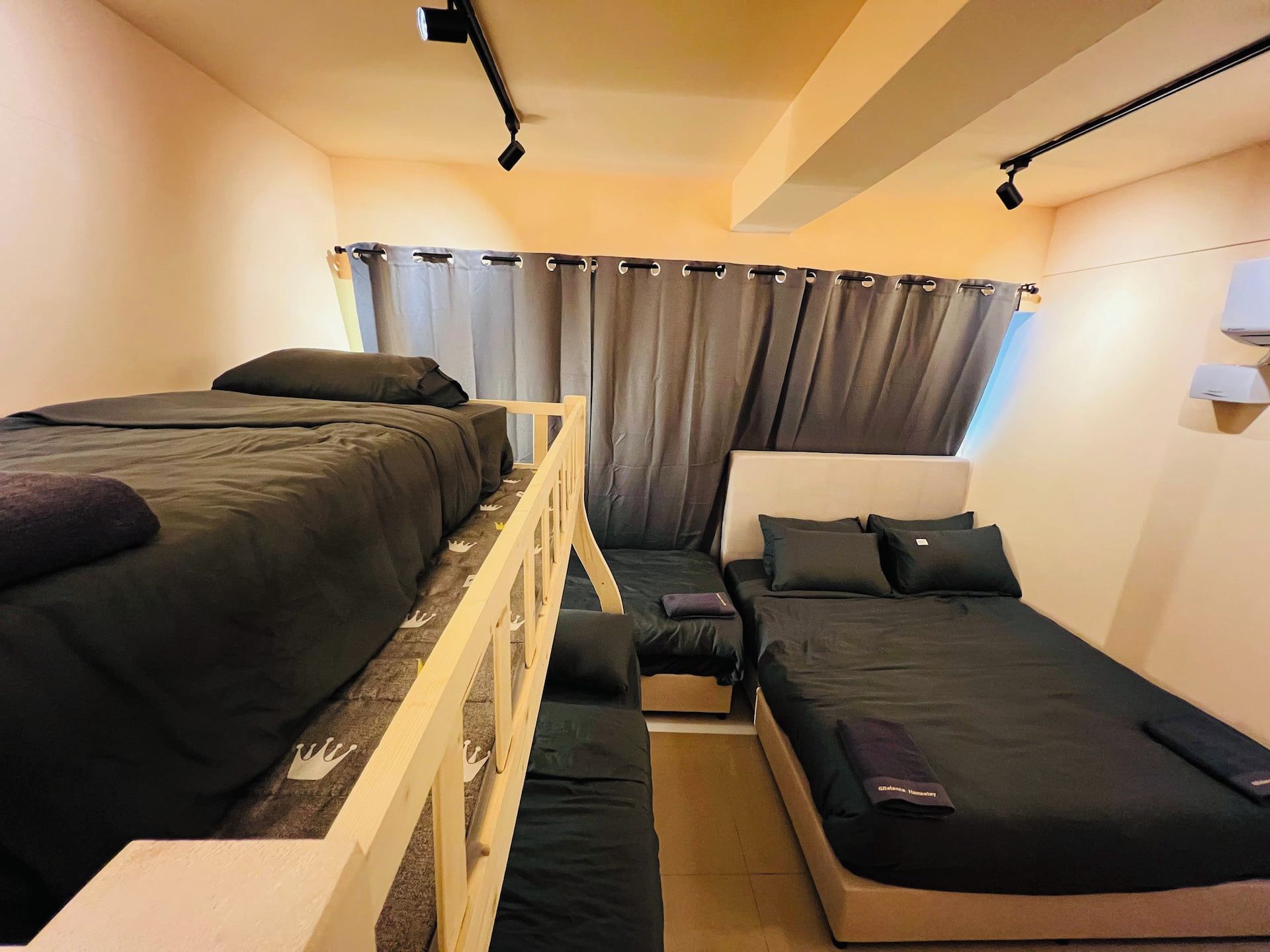 A compact hotel room with two single beds, a small sofa, and a wooden partition.