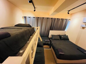 A compact hotel room with two single beds, a small sofa, and a wooden partition. - 16Pax Sunway Pyramid Karaoke Homestay by 4Balance (Petaling Jaya)