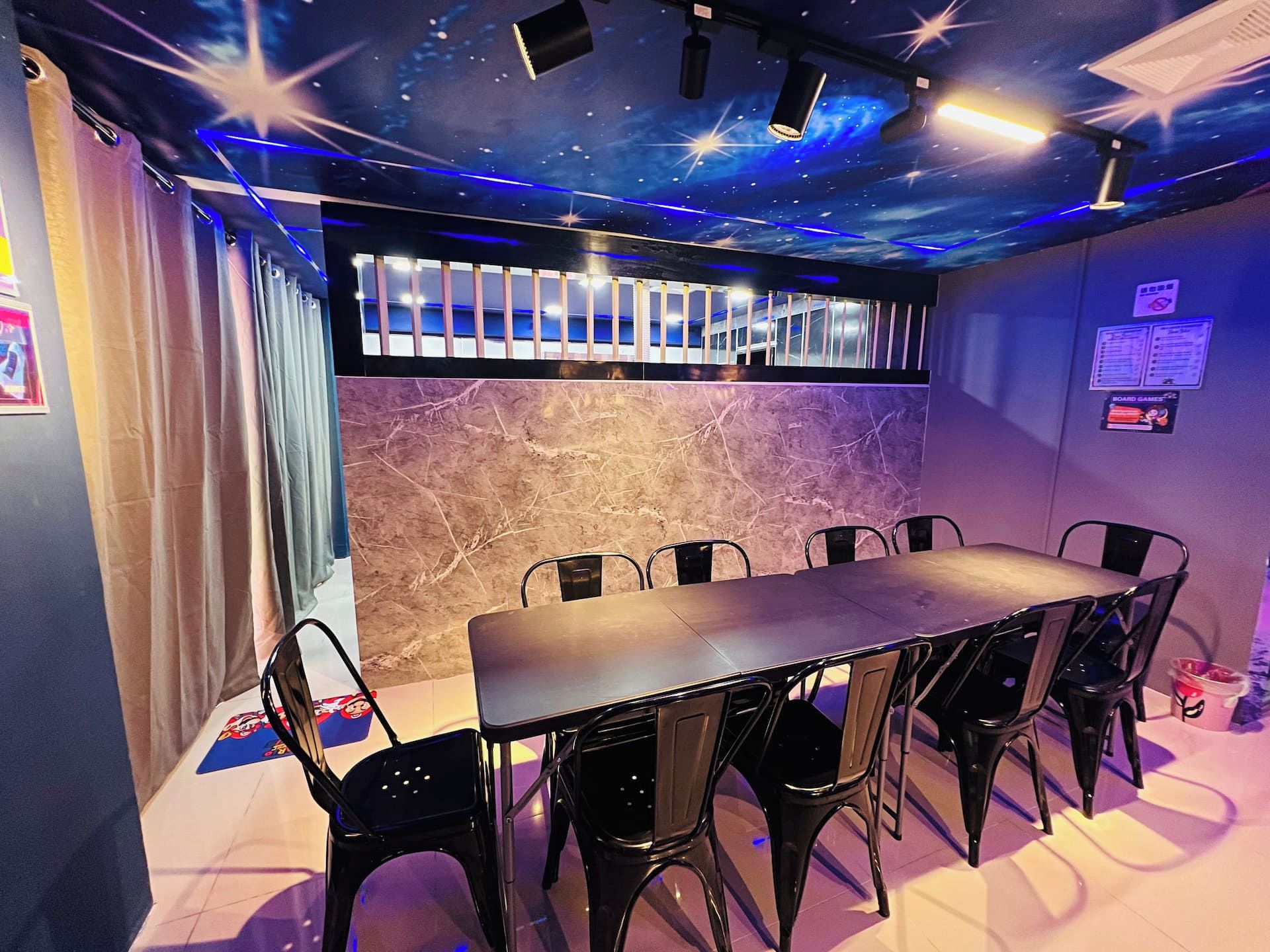 A room with a long table and chairs, a ceiling with star projections, and a wall with a marble texture.