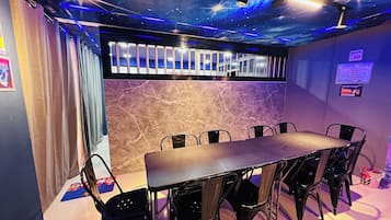 A room with a long table and chairs, a ceiling with star projections, and a wall with a marble texture.