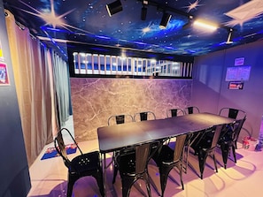 Une pièce dotée d’une longue table et de chaises, d’un plafond orné de projections d’étoiles et d’un mur à la texture de marbre.