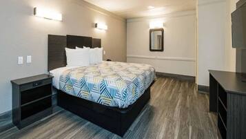 A hotel room with a bed, bedside tables, a mirror, and a TV stand.