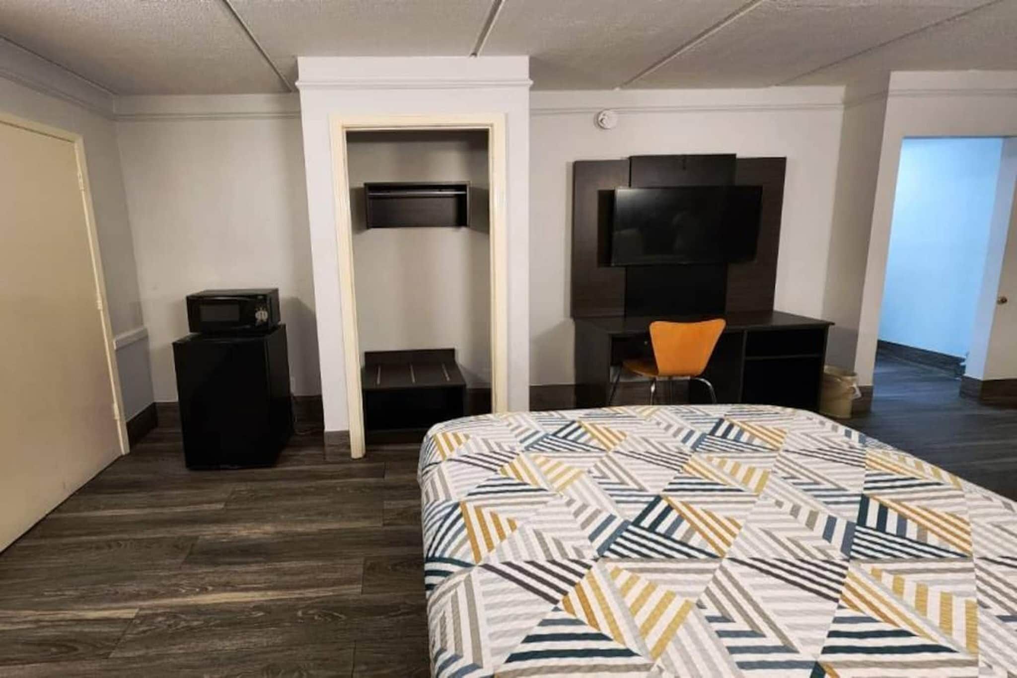 Una habitación de hotel con una cama, un escritorio, una silla, un televisor y un microondas.