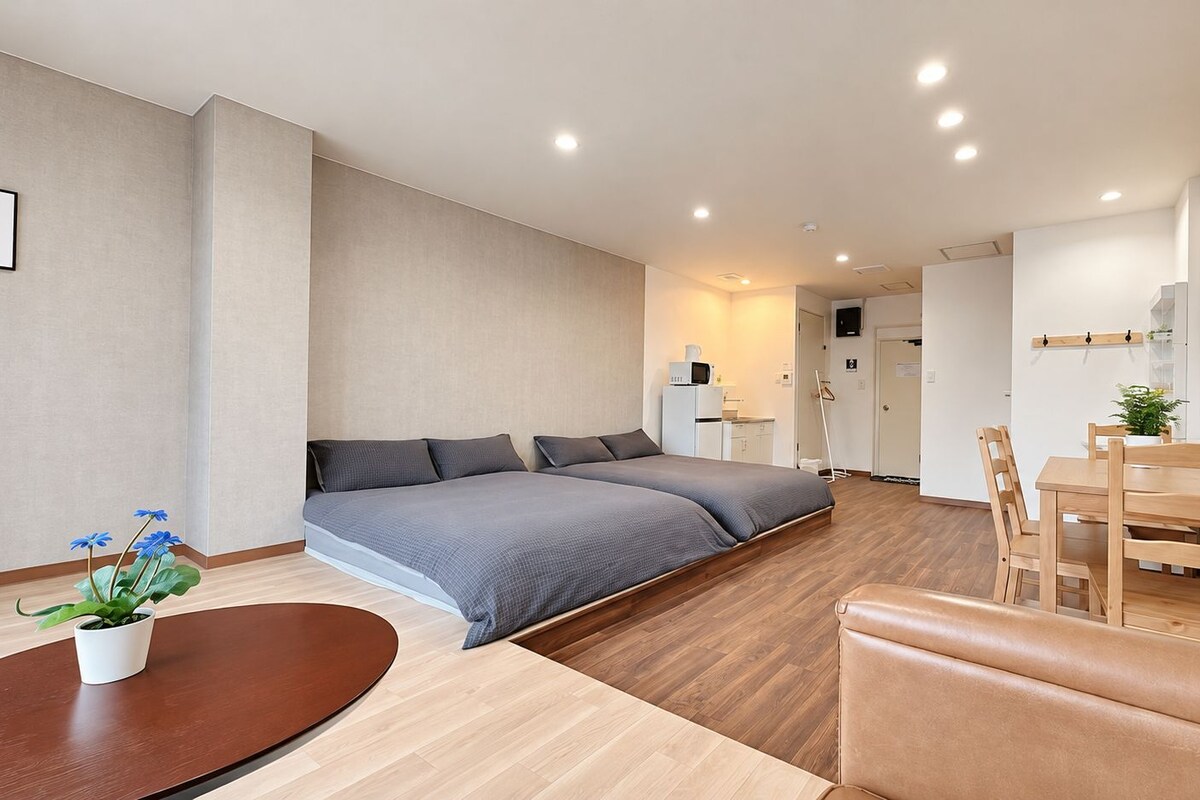 A modern bedroom with a bed, bedside table, and a potted plant.