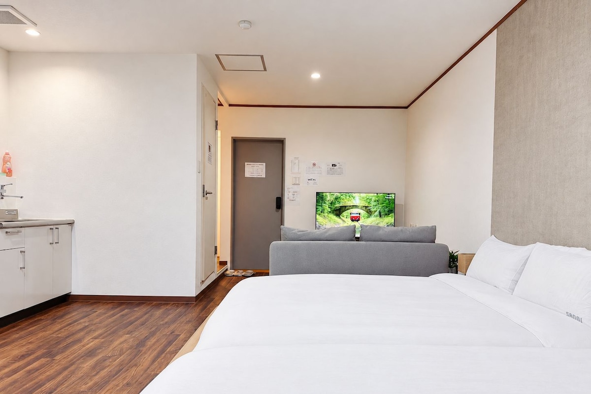 A hotel room with a bed, a television, a desk, and a wardrobe.