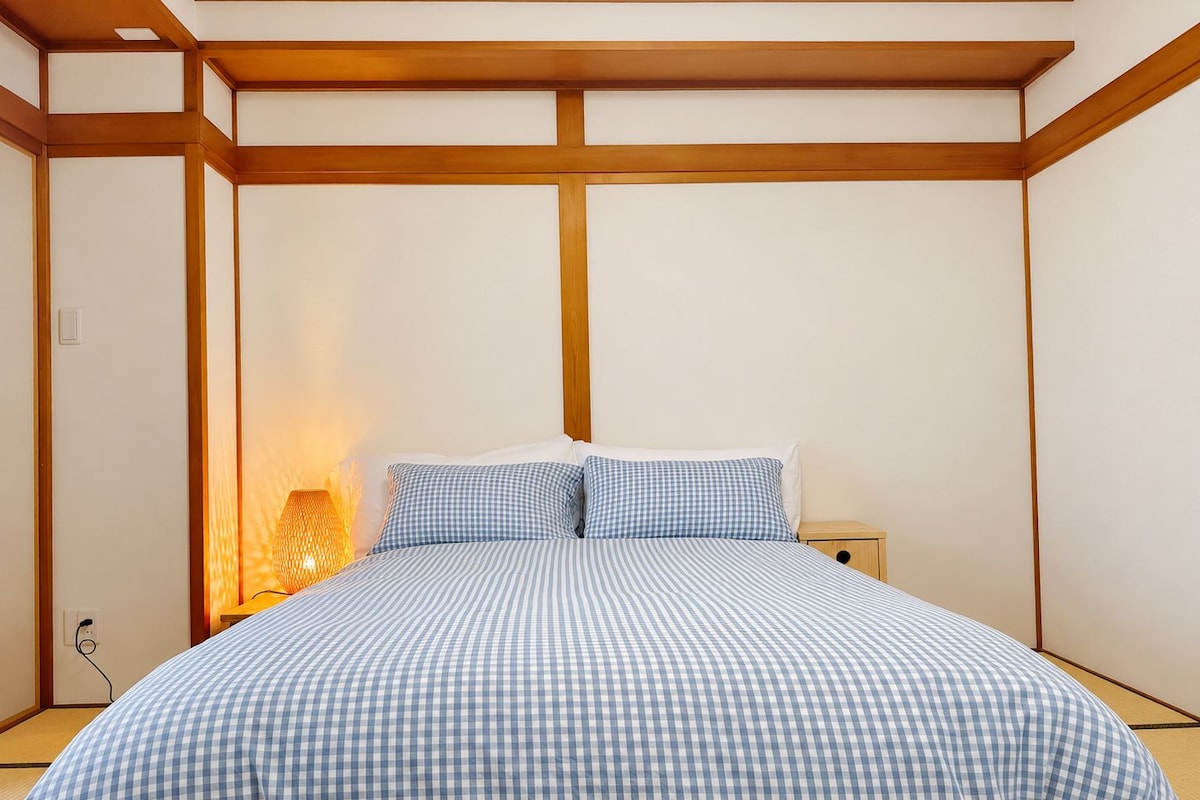 A bedroom with a bed, a nightstand, and a lamp.