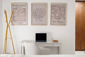 A minimalist room with a desk, laptop, and framed artwork on the wall. - FIRST CLASS | 1BR | Elegant w/ Dubai Mall Access (Dubai)