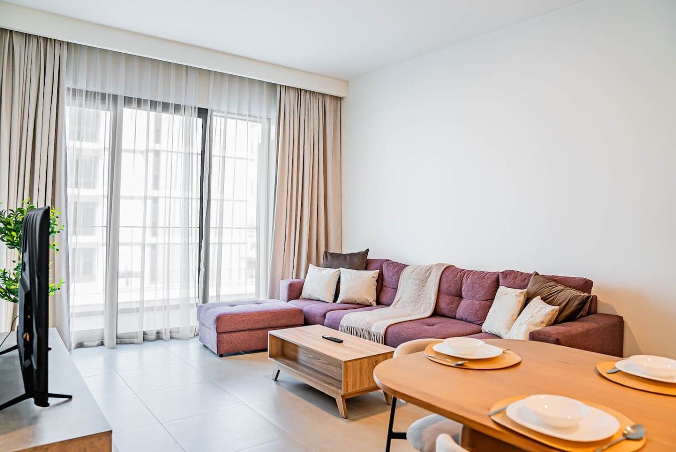 A modern living room with a sofa, coffee table, and dining table set for four.