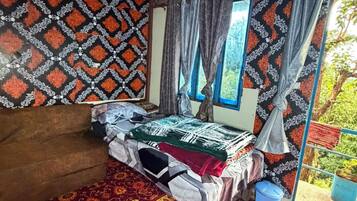 A room with a bed, a window with curtains, a patterned wall, and a red carpet.