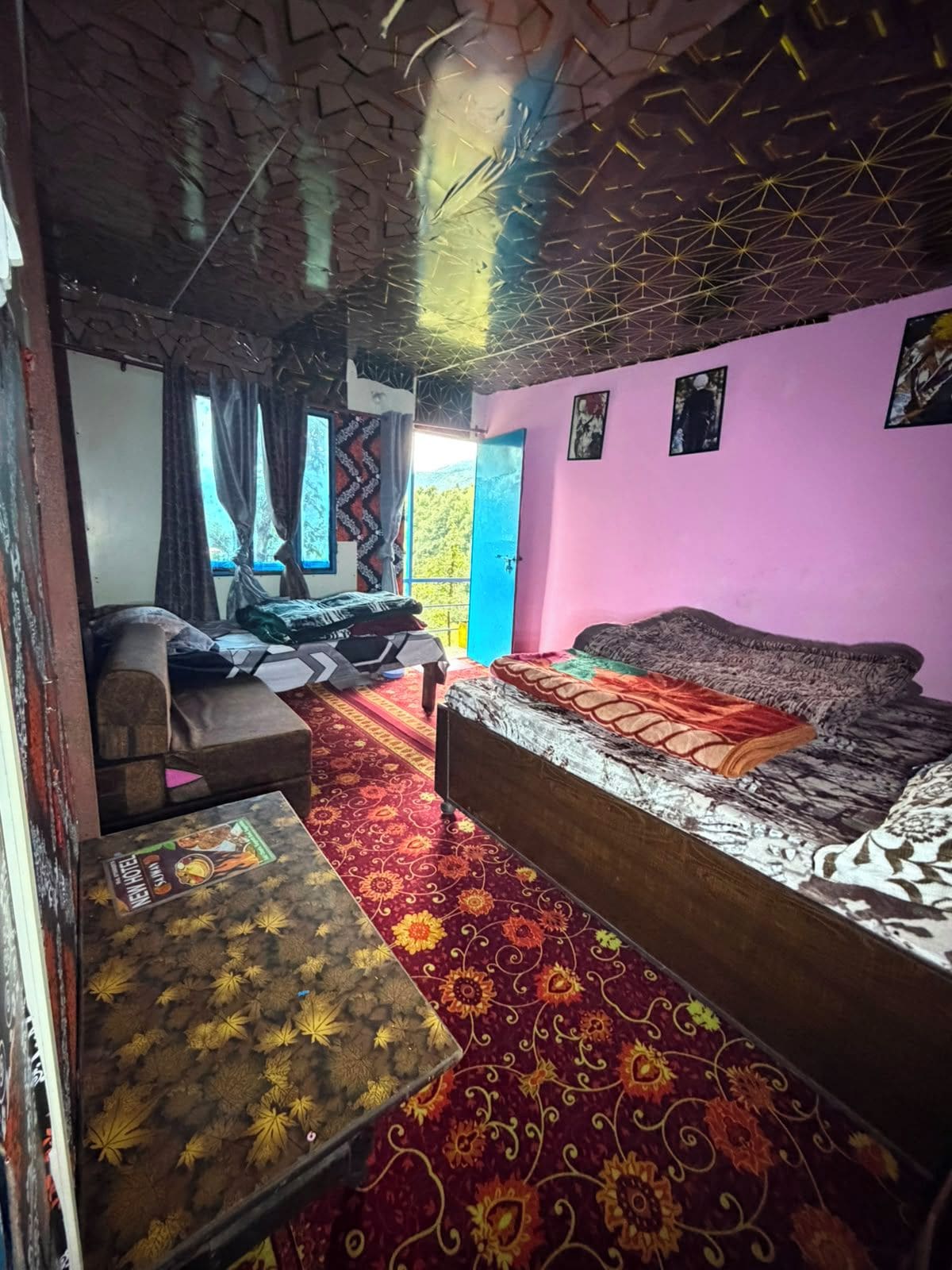 A room with a bed, a sofa, a small table, and a window with curtains.