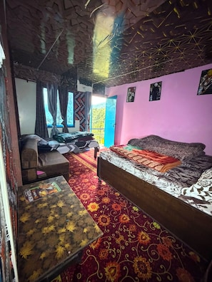 Habitació amb llit, sofà, taula petita i finestra amb cortines.