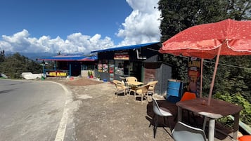 A roadside hotel with outdoor seating and a blue awning.