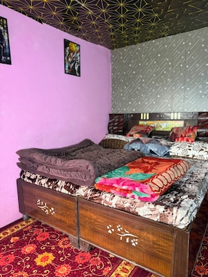A bedroom with a bed, a patterned wall, and a decorative ceiling. - New Hotel Sajwan (Ukhimath)