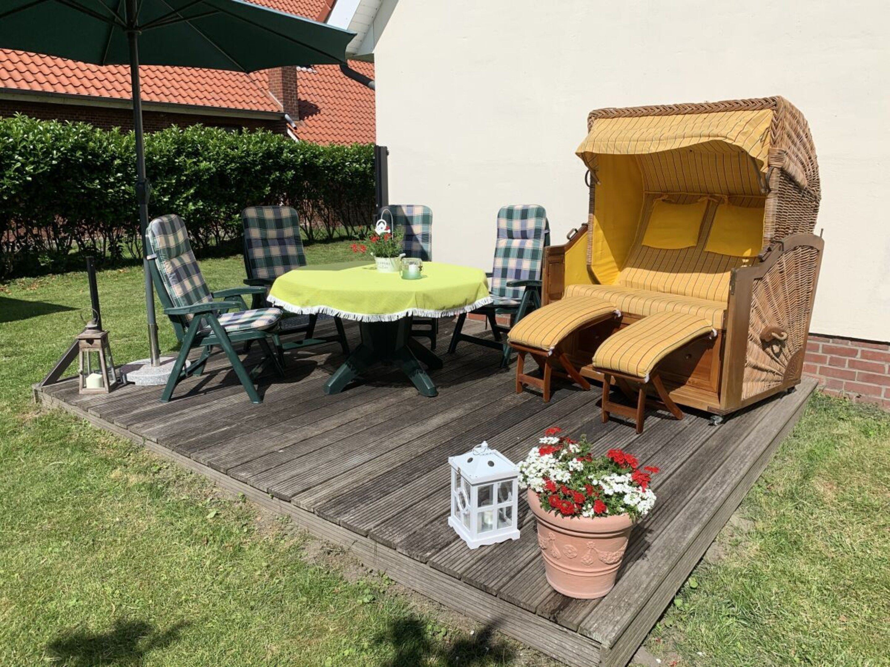A patio with a round table, two chairs, a wicker sofa, and a potted plant.