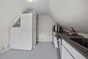 Une cuisine de taille réduite avec des meubles blancs, un plan de travail et un four encastré.