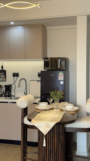 A modern kitchen with a built-in microwave, a coffee machine, and a dining area with a table set for two. - Modern 1 bedroom Westlands Nairobi (Nairobi)