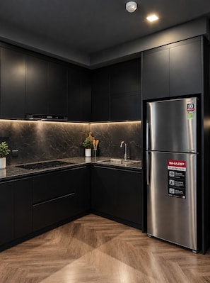 Eine moderne Küche mit dunklen Schränken, einem Edelstahlkühlschrank und einer Marmor-Spritzschutzwand.
