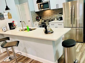 Una cocina moderna con una isla central, electrodomésticos de acero inoxidable y taburetes de bar.