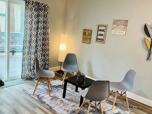 Una habitación con una mesa de comedor, cuatro sillas, una lámpara y decoración en la pared.