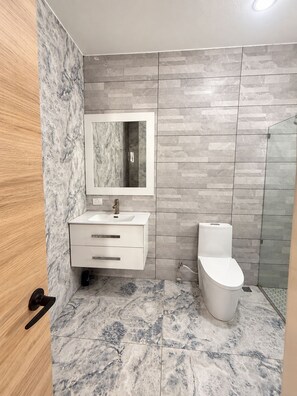 Ein modernes Badezimmer mit einem мраморной раковиной, einer Duschkabine aus Glas und einem WC.