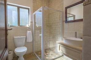 Ein Badezimmer mit Toilette, Duschkabine, Waschbecken und Spiegel.