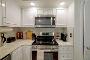 A kitchen with white cabinets, a stainless steel microwave, a stove, and a coffee machine. - The Boise Retreat | Spacious Home, Game Room! (Boise)