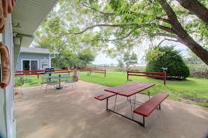 An outdoor patio with a picnic table and benches, surrounded by a wooden fence and trees. - Harlan County Lake View Cabin by ATV Trails (Republican City)