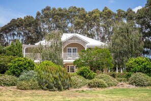 A two-story house with a balcony and a garden in front. - Windmill Farm | Space, Serenity | Rural Views (Forest Grove)