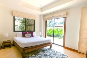Un dormitorio con una cama grande, una mesita de noche, una ventana con persianas y vistas al exterior.