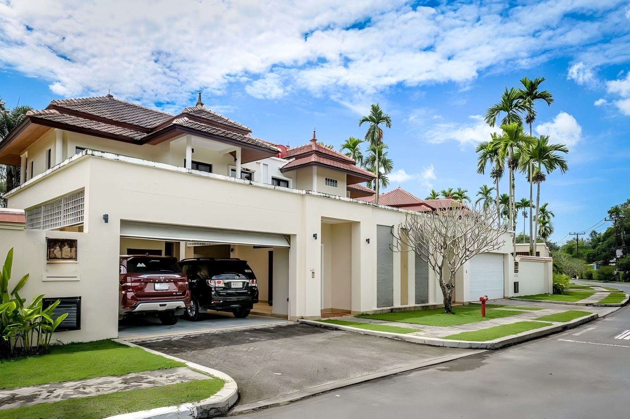 A two-story residential building with a garage, parked cars, and a well-maintained lawn.