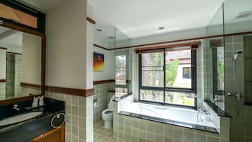 A modern bathroom with a large mirror, a bathtub, a shower, and a toilet.
