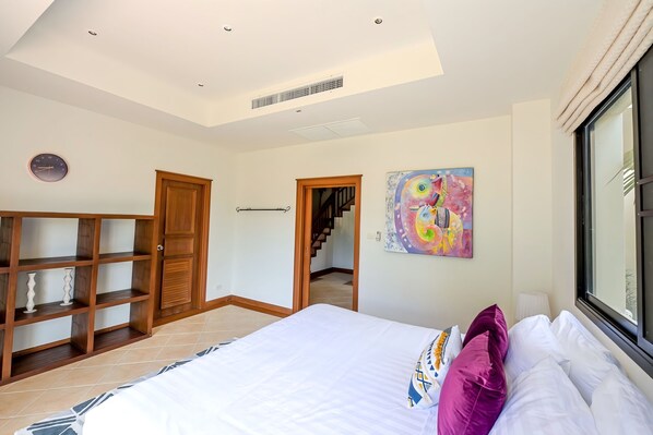 A bedroom with a bed, a wardrobe, a painting, and a window.