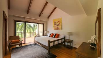 Un dormitorio con una cama grande, una silla, una mesa y un cuadro en la pared.