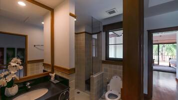 A modern bathroom with a large mirror, a sink, a toilet, and a shower area.
