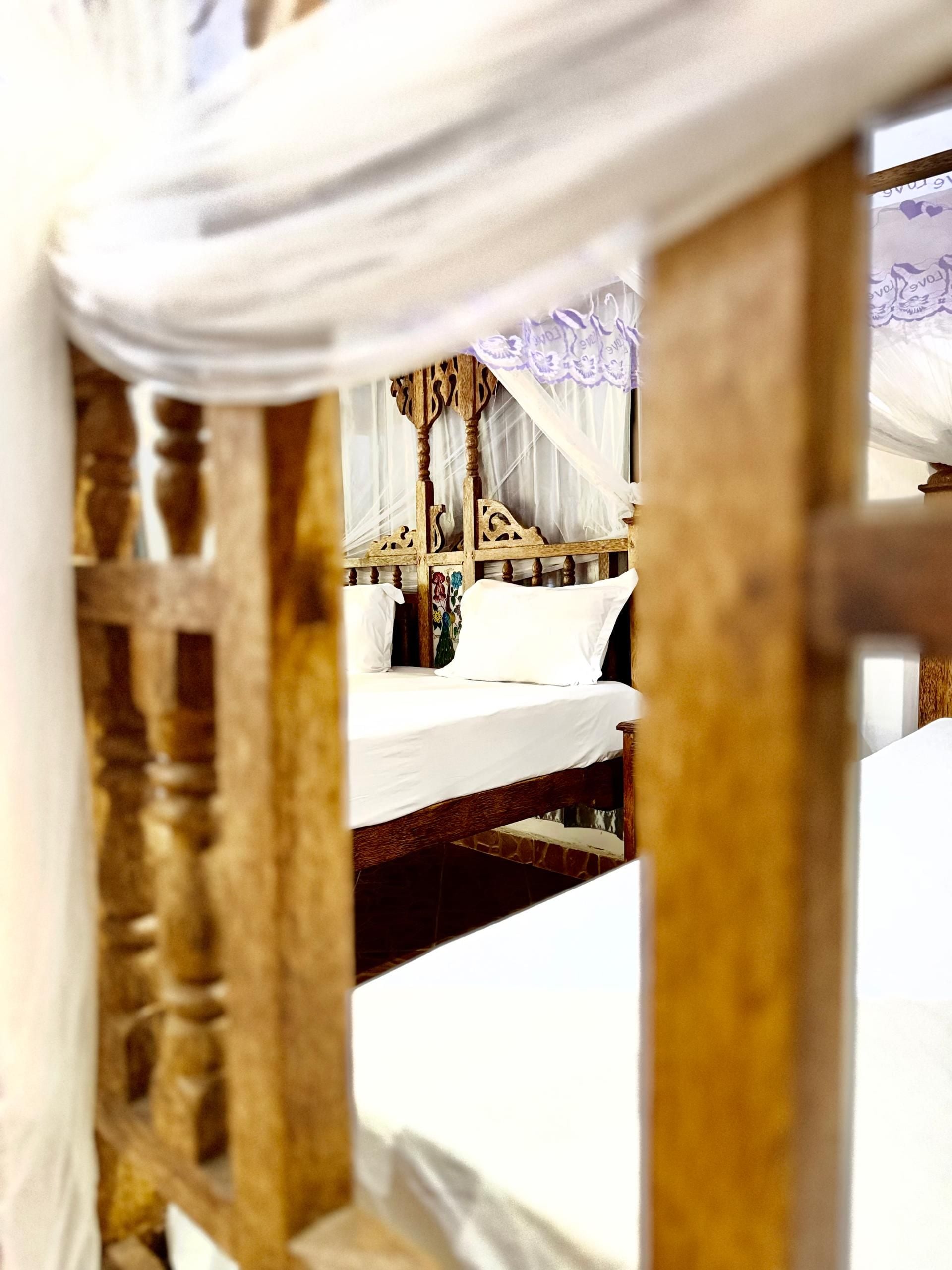 Una cama con dosel y cabecera de madera.