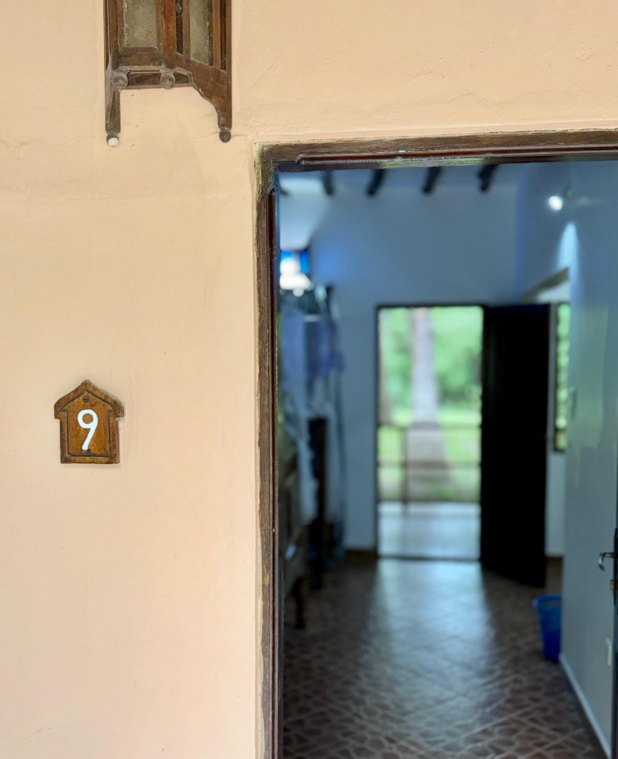 Ein Flur mit einer Tür zu einem Zimmer, einer Nummer und einem Fenster mit Blick auf Grünflächen.