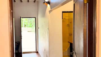 A hallway with a tiled floor, a door leading to a bathroom, and a view of the outside.