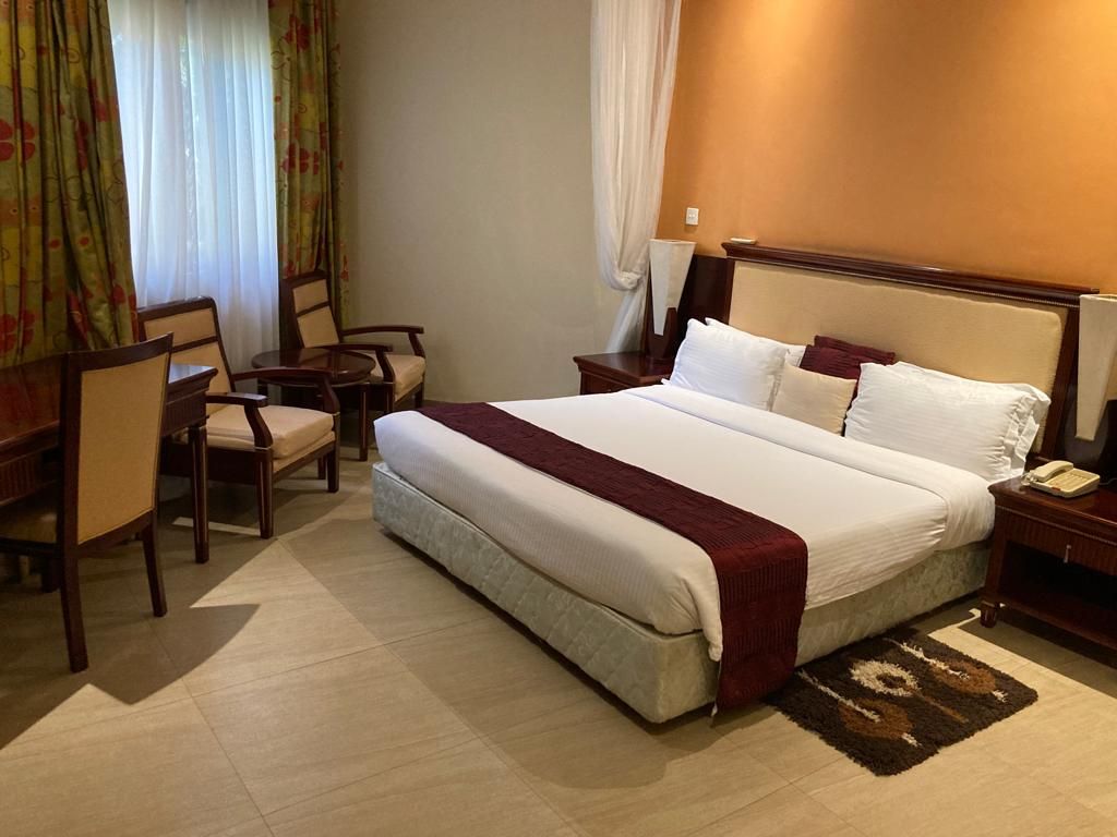 A hotel room with a large bed, a desk, and a chair.