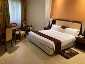 Ein Hotelzimmer mit einem großen Bett, einem Schreibtisch und einem Stuhl.
